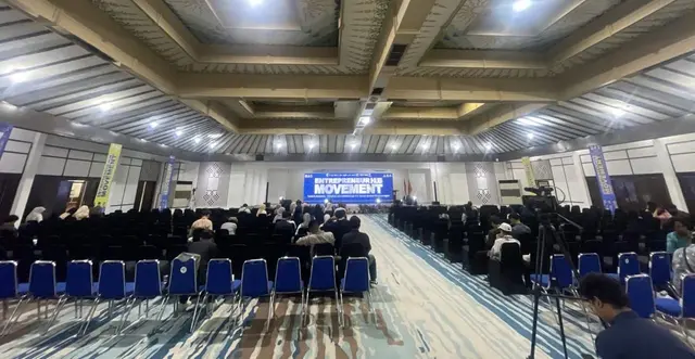 Aula seminar dari belakang, kursi peserta berderet menghadap layar LED