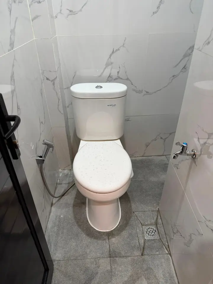 Bilik toilet dengan kloset duduk, semprotan, dan keran